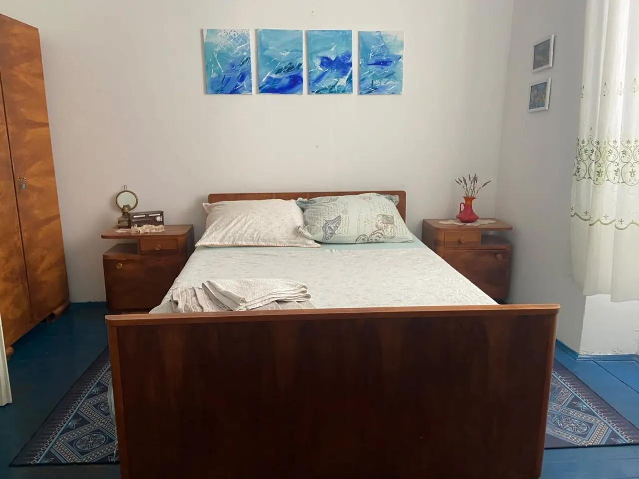 Bedroom with a retro walnut double bed, matching bedside tables and blue paintings above the bed