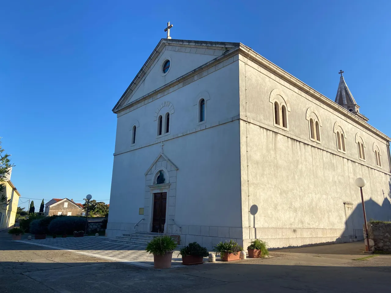 White stone church on the village square under a blue sky